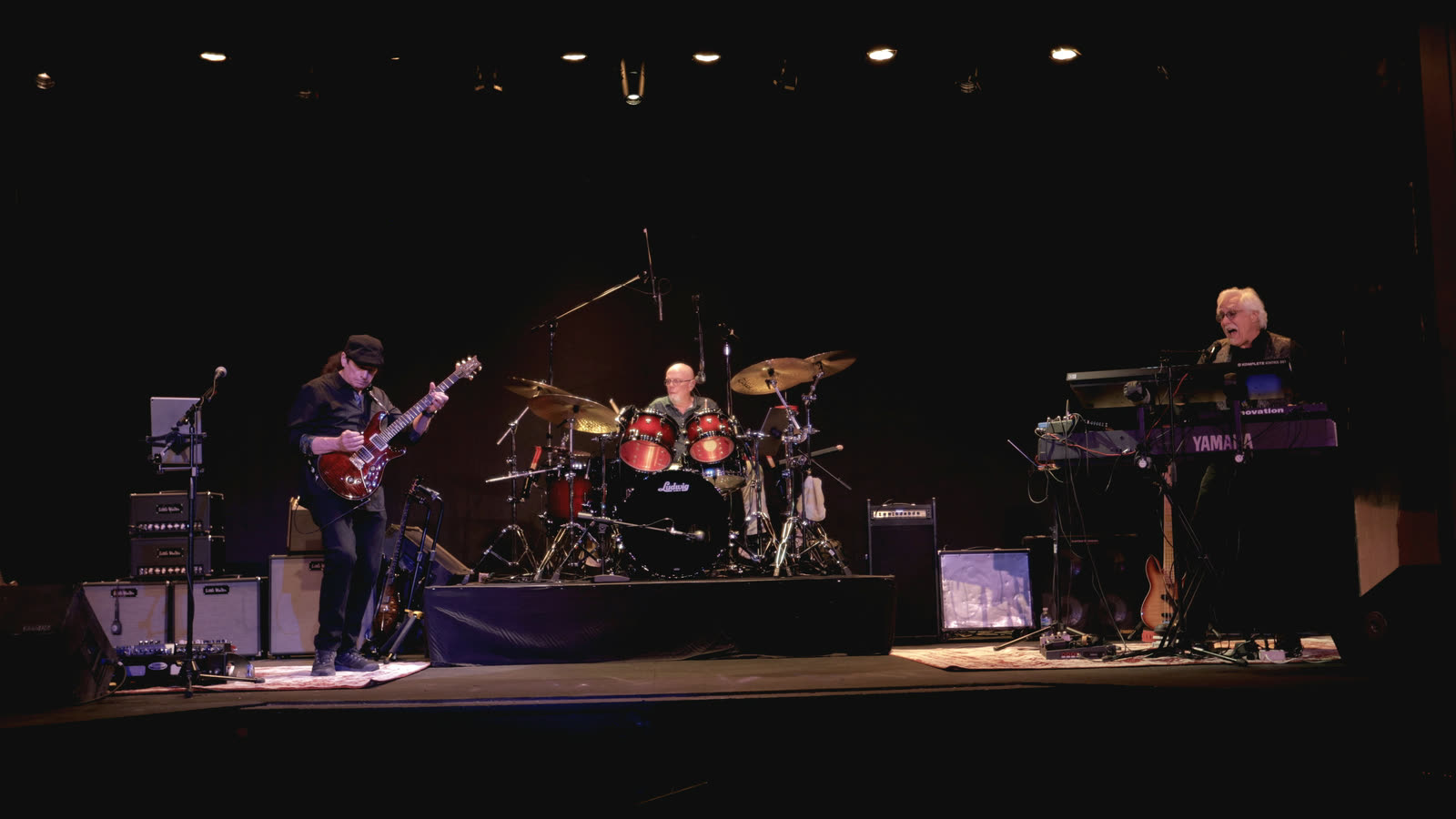 The whole band on stage under the house lights.