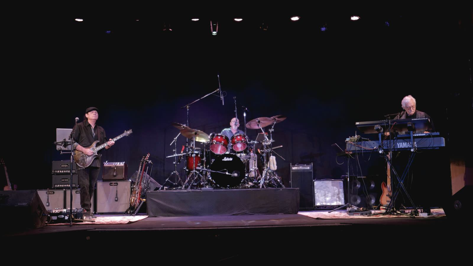 The band on stage: Allen on guitar at left, Ed on drums in the middle, and Rico at the keyboards on the right.