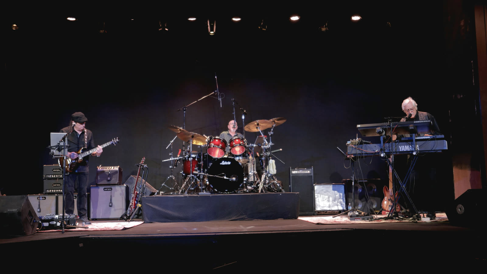 A wide view of the stage: Allen on guitar at left, Ed on drums, and Rico at the keyboards on the right.